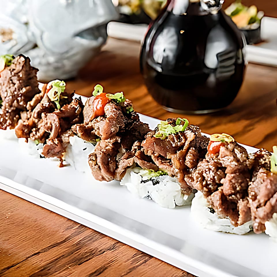 Sushi Cafe's beef sushi rolls with green onions and sauce on a white plate.